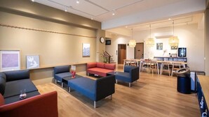 A modern hotel lobby with sofas, a dining area, and a clock on the wall. - Letaotao Inn (Ji'an)