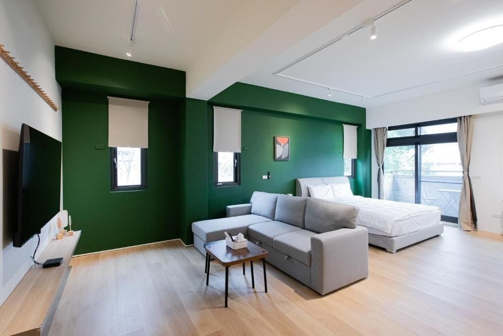 A modern living room with a sofa, a small table, a bed, and a TV.