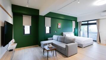 A modern living room with a sofa, a small table, a bed, and a TV.