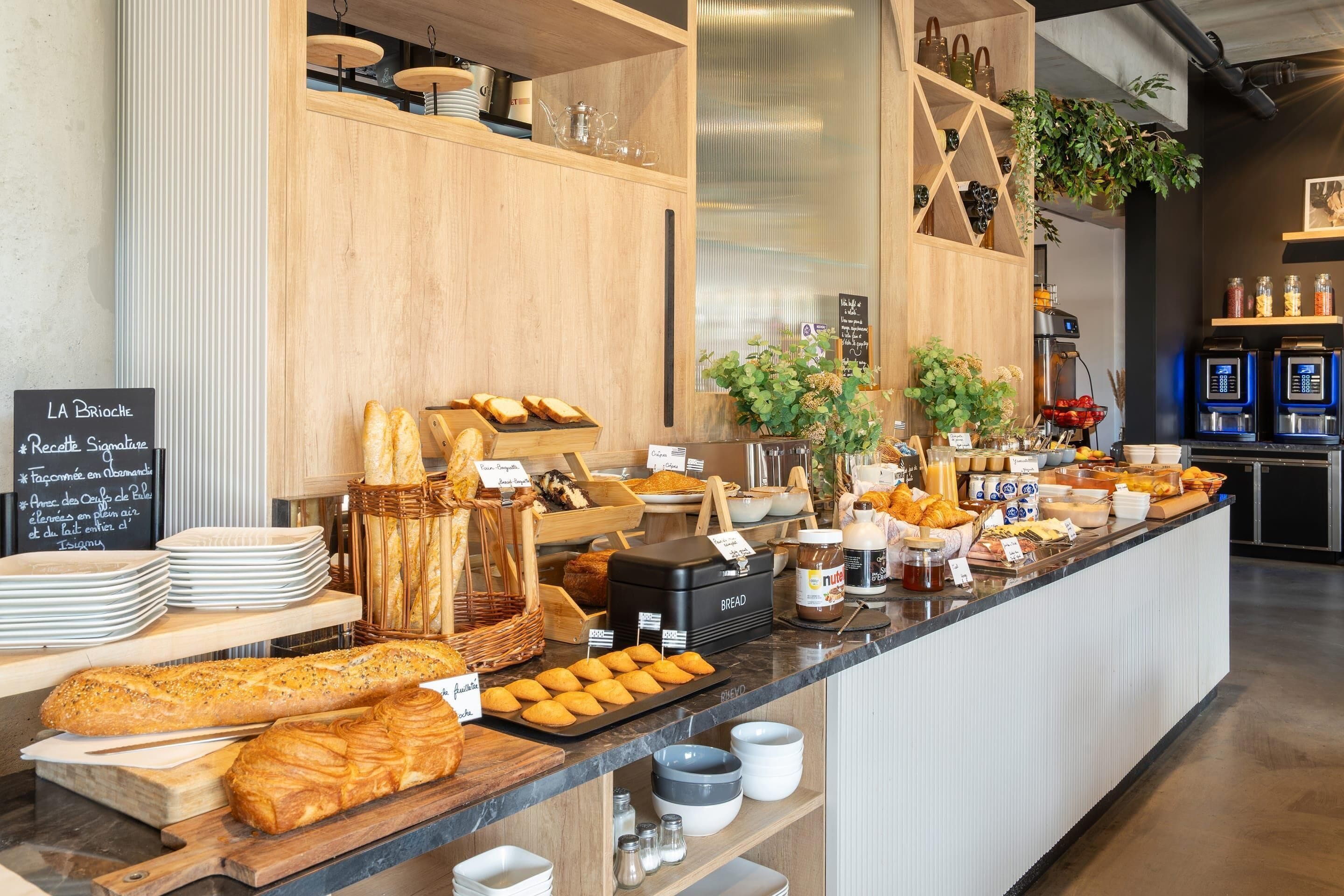 A breakfast buffet with various bread, pastries, and condiments.