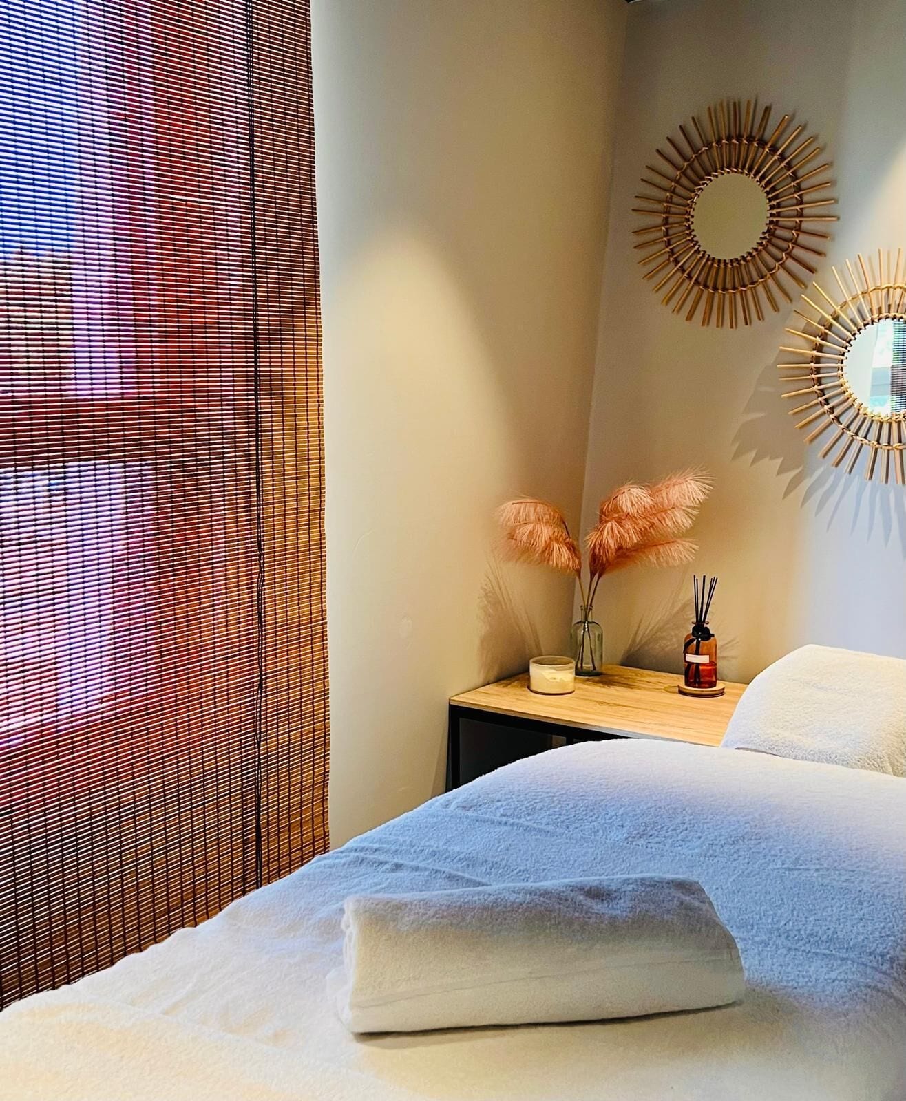 Une chambre d’hôtel avec un lit, une table de chevet avec une lampe et un vase, et un élément décoratif mural.