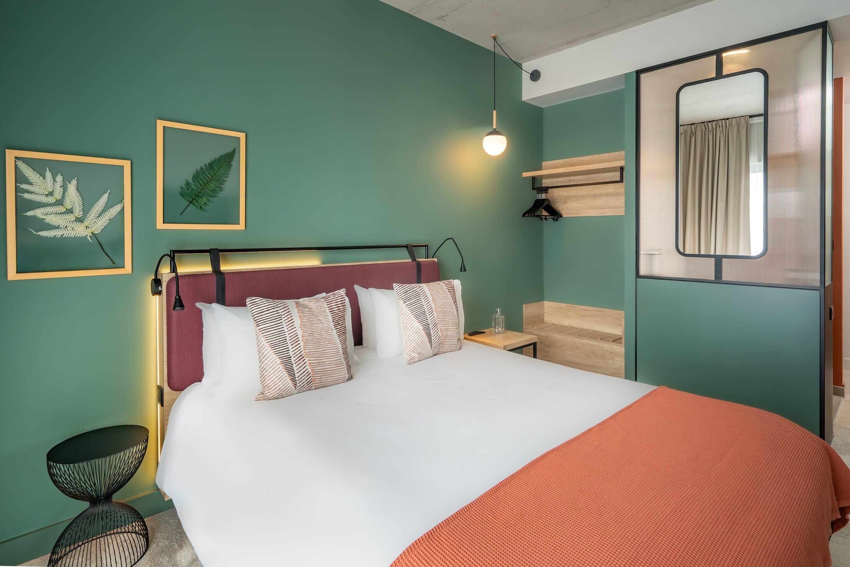 A neatly made bed with a white and orange blanket, a headboard, and multiple pillows.