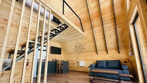 Een houten interieur met een trap, een bank en een bureau.