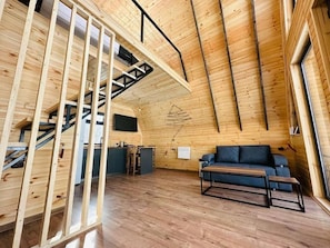 A wooden interior with a staircase, a sofa, and a desk.