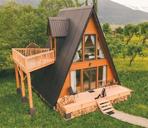 A wooden cabin with a balcony, a deck, and a staircase leading to the entrance.