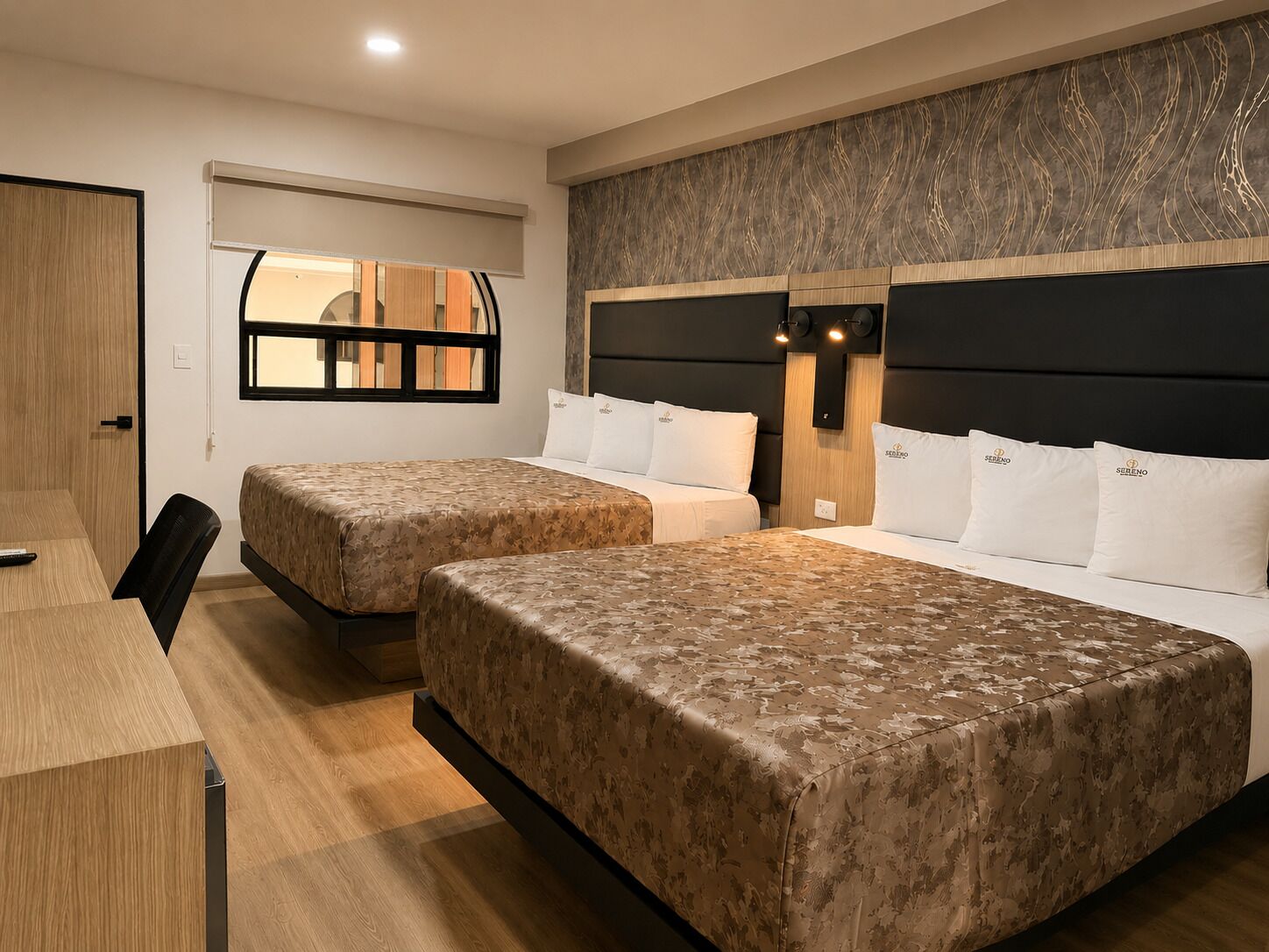 Habitación de hotel con dos camas, un escritorio y una ventana.