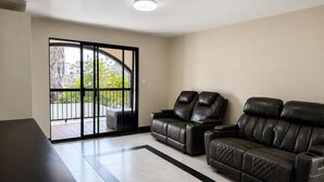 A living room with a sofa, two recliners, a coffee table, and a sliding glass door leading to an outdoor area.