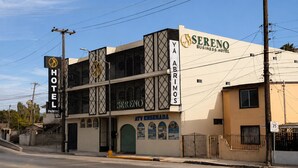 A hotel with a sign for 'SERENO BUSINESS HOTEL' and 'YA ABRIMOS' on the facade.