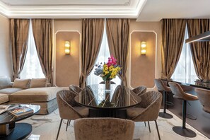 Ein modernes Hotelzimmer mit einer Couch, einem runden Esstisch und Stühlen.