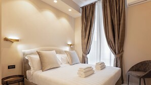 Una habitación de hotel con una cama, una silla, una mesita de noche y cortinas.