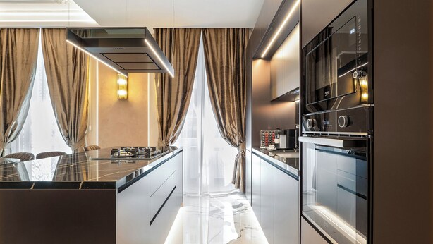 Una cocina moderna con una isla central, horno empotrado y electrodomésticos de acero inoxidable.