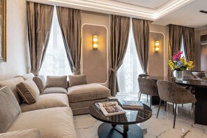 Ein modernes Wohnzimmer mit einer Couch, Sesseln, einem Couchtisch und einem Essbereich mit einer Blumenvase.