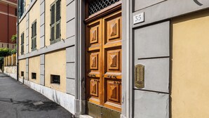 Un edificio con una puerta de madera grande, un letrero con el número '35' y un respiradero metálico en la pared.