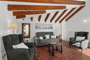 A living room with a sofa, two armchairs, a coffee table, wooden beams, a lamp, and a view of the outdoors. - Can Mayol, beautiful, newly refurbished village house at few steps from centre. (Fornalutx)