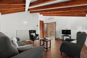A living room with a sofa, armchairs, a coffee table, a TV, and a door leading to a balcony. - Can Mayol, beautiful, newly refurbished village house at few steps from centre. (Fornalutx)