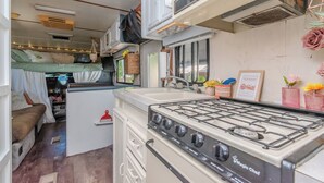 Een compacte RV-keuken met een kookplaat, spoelbak en een klein eethoekje.