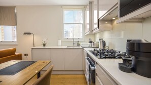 Una cocina moderna con estufa integrada, una mesa de comedor y una ventana con vistas a la ciudad.