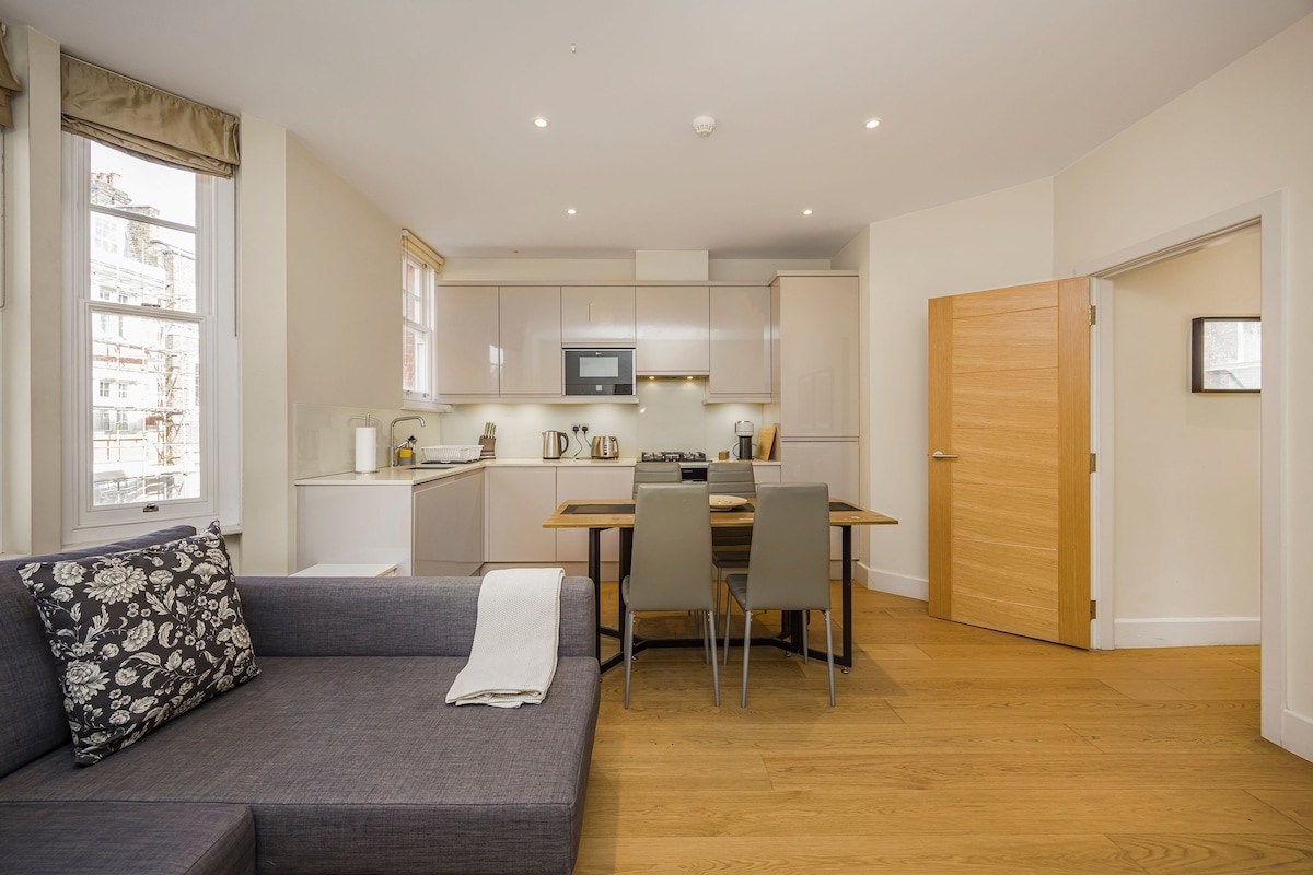 Una cocina moderna con comedor, un sofá con una manta y una puerta de madera.