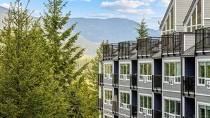 A multi-story building with balconies, large windows, and a mountainous backdrop. - Christmas in Whistler!   1 bedroom + den condo. Walk to the slopes!  (Whistler)