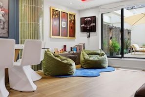 Ein modernes Wohnzimmer mit einer Couch, Sitzsäcken, einem Couchtisch und Kunstwerken an der Wand.