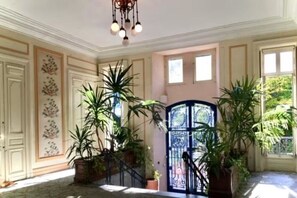 Un hall d’entrée spacieux, agrémenté d’un grand escalier, de plantes en pot et d’une porte décorative.