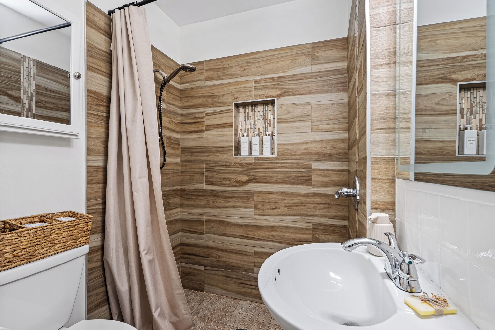 A bathroom with a shower, a sink, a mirror, and a toilet.
