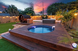 A wooden deck with a hot tub, a wooden barrel, and a wooden fence with string lights. - Palm Paradise Resort! Beach Area, Pool, Sauna, Cold Plunge, Hot Tub - Zen Zone (Lake Worth Beach)