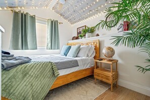 A bedroom with a wooden bed, a globe on a nightstand, and a window with curtains. - Palm Paradise Resort! Beach Area, Pool, Sauna, Cold Plunge, Hot Tub - Zen Zone (Lake Worth Beach)