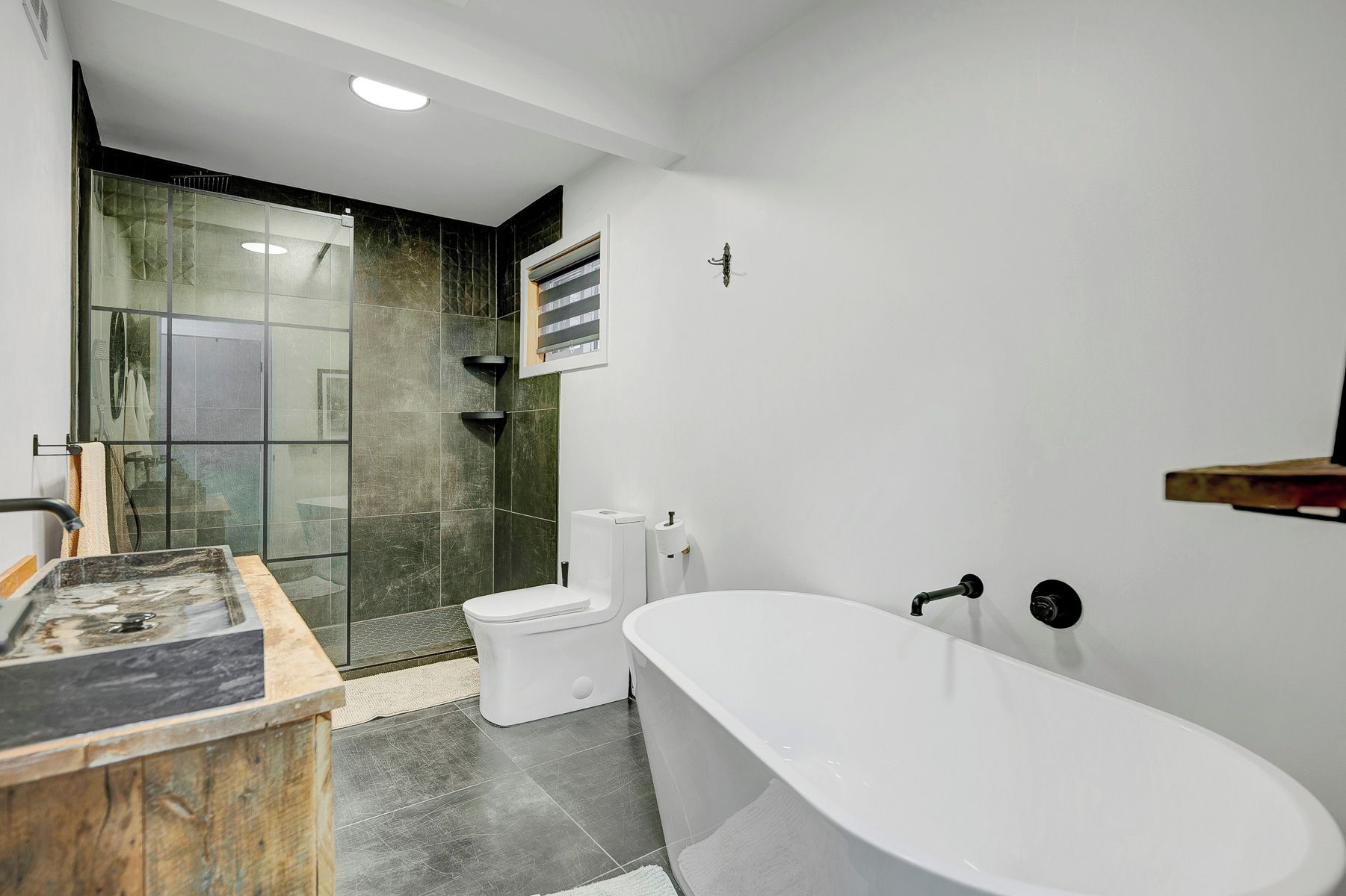 Une salle de bain moderne avec une baignoire sur pieds, une douche à parois de verre et des toilettes.