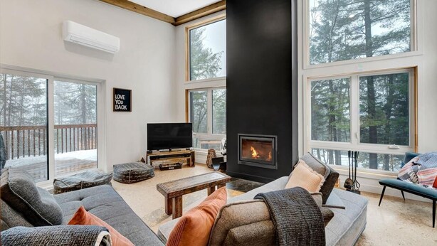 A modern living room with a fireplace, large windows, and a television.