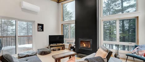 A modern living room with a fireplace, large windows, and a television.