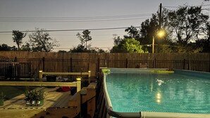 A swimming pool with a wooden deck and a fence in the background.