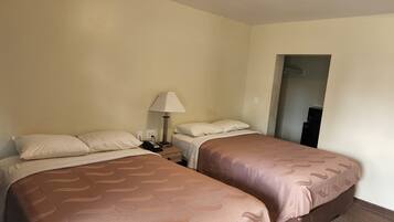 Una camera d'albergo con due letti, un comodino con una lampada e un armadio.