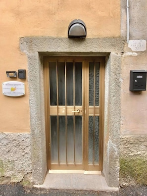 A building entrance with a metal gate, a mailbox, and a sign indicating the name 'Affittacamere La casa a Chioccoli.' - The Spiral House (Liguria)