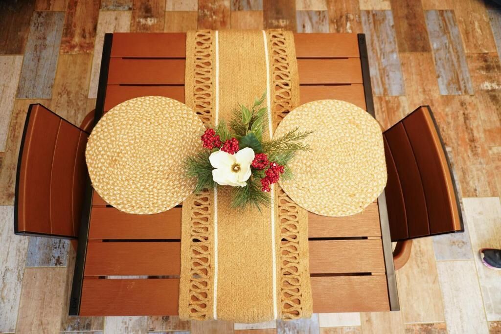 A dining table with a central floral arrangement, two round placemats, and matching chairs.