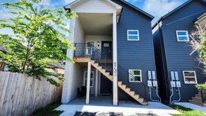 A two-story residential building with a covered front porch, a staircase, and a visible electrical box.
