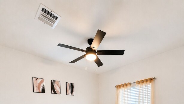A bedroom with a bed, a bedside table, a ceiling fan, and a window with curtains.