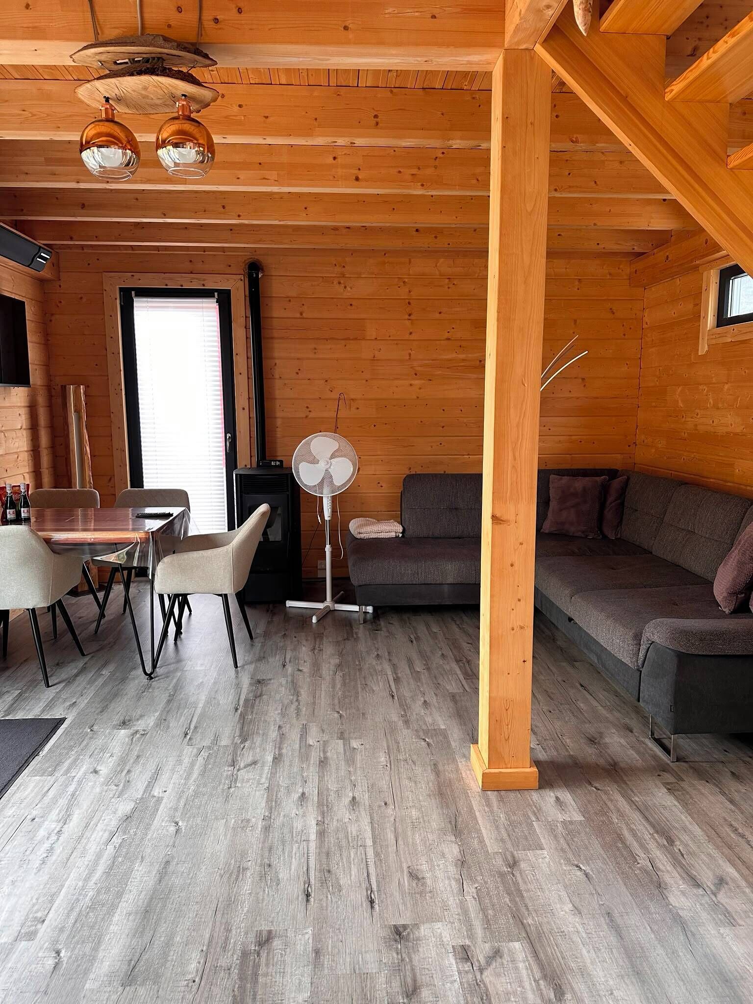 A wooden interior with a dining area, sofa, and fan.