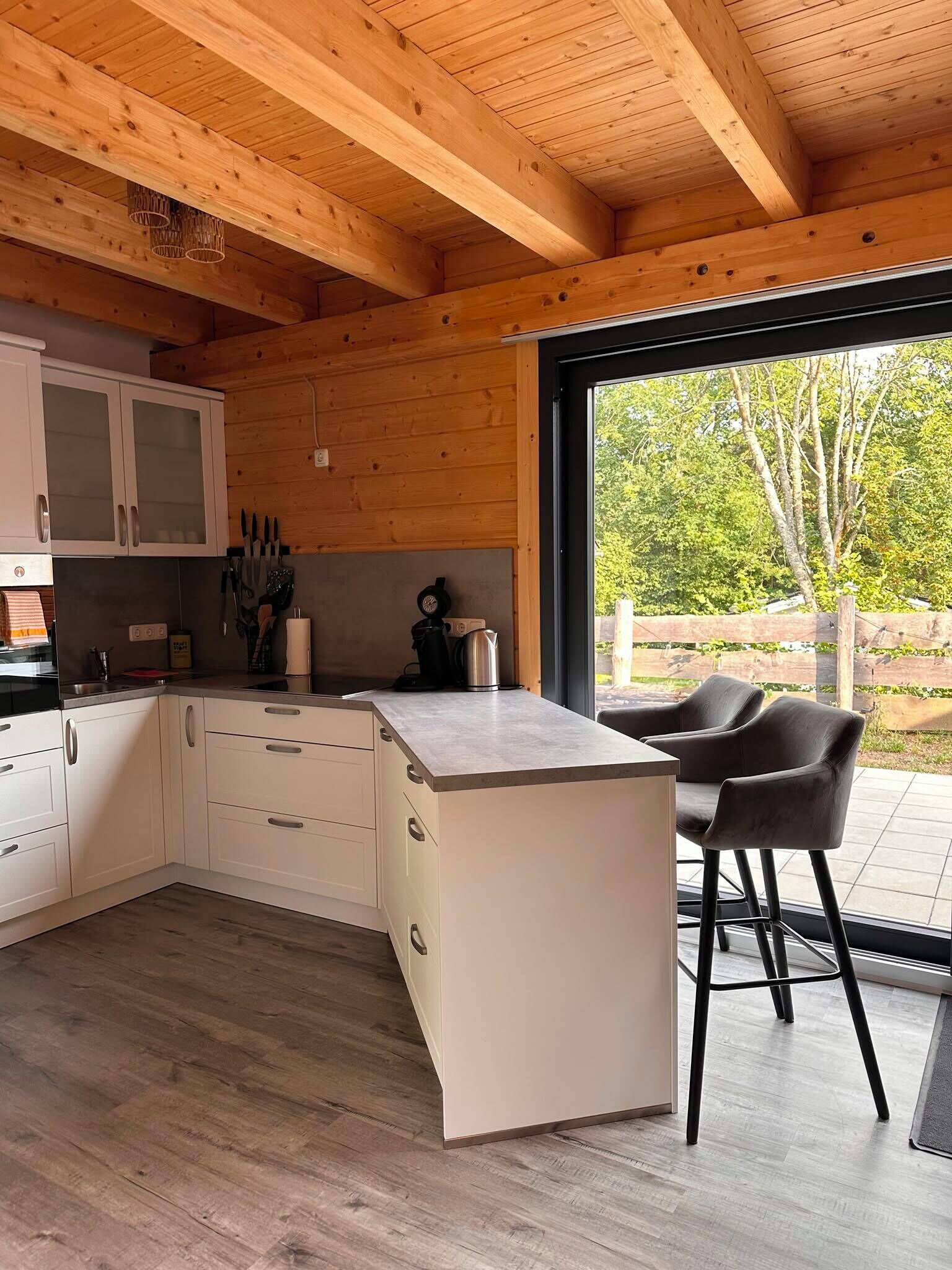 A modern kitchen with white cabinets, a countertop, and a dining area with two chairs.