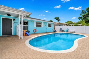 A swimming pool with a tiled deck, a door, and a small outdoor seating area with chairs. - Family and dog friendly home with private pool (Largo)