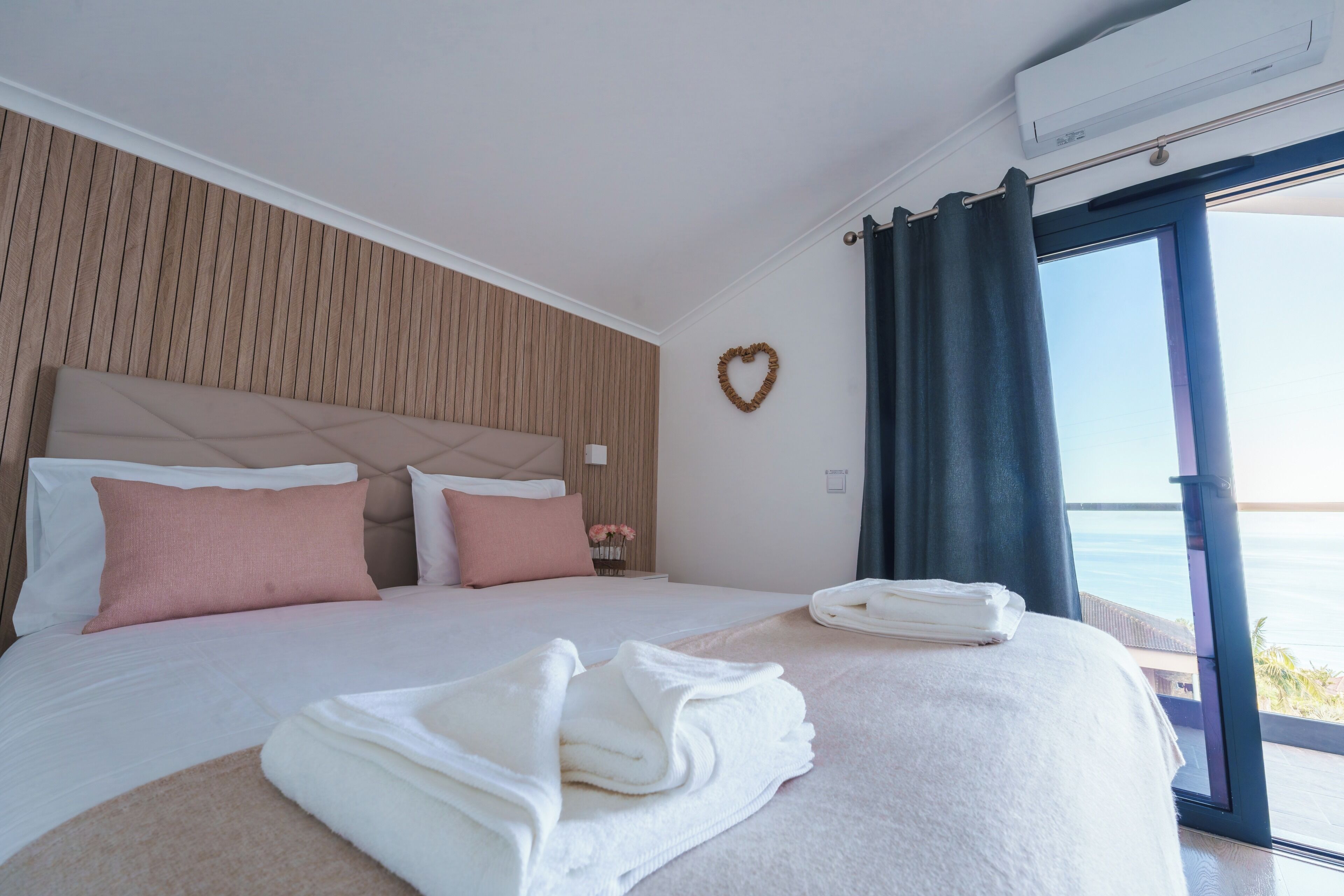Ein Hotelzimmer mit einem Bett, einer herzförmigen Dekoration und Blick durch ein Fenster.