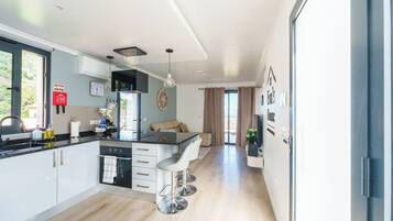 A modern kitchen with a central island, a dining area with a sofa, and a view of the outdoors.