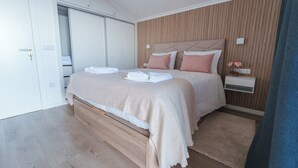 A modern bedroom with a bed, bedside tables, and a wardrobe.