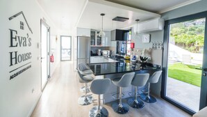 A modern kitchen with a central island, bar stools, and a view of the outdoors.