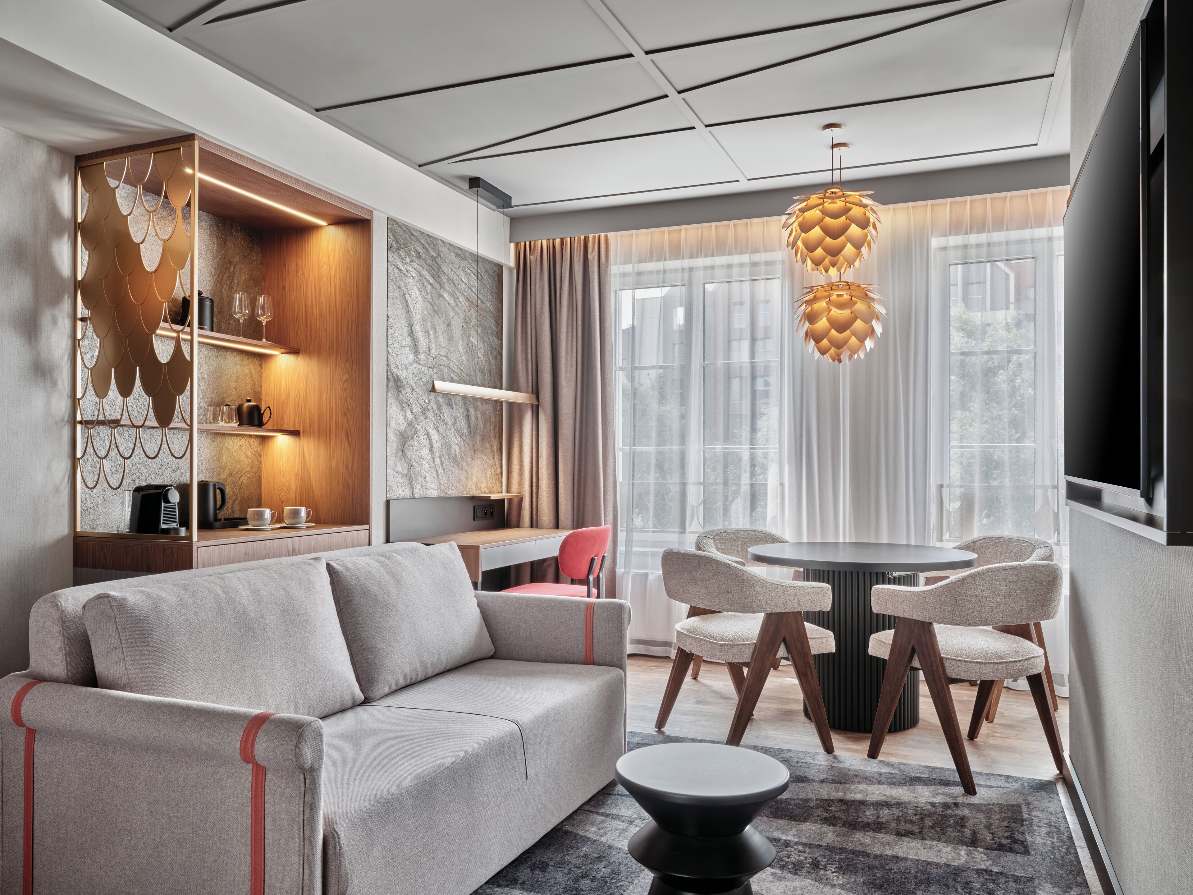 A modern living room with a sofa, dining table, chairs, and a unique pendant light.