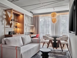 Una sala de estar moderna con sofá, mesa de comedor, sillas y una lámpara colgante original.