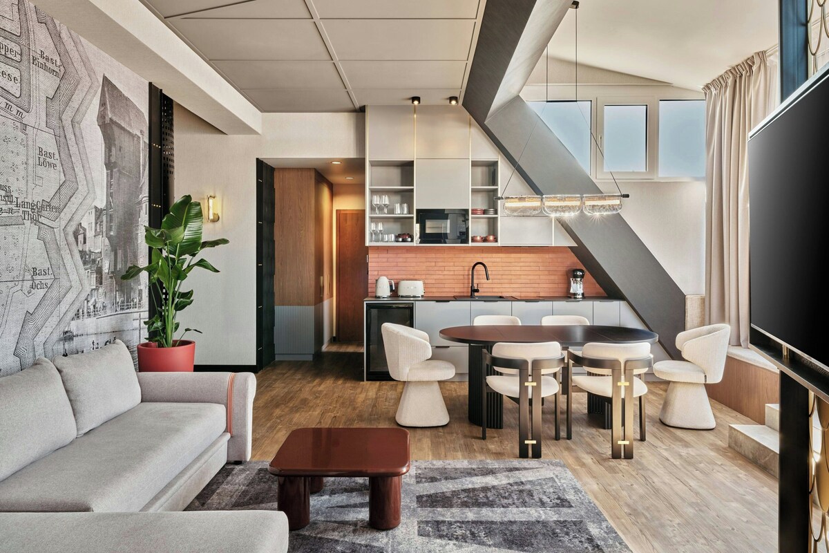 A modern living room with a sofa, coffee table, and dining area with chairs.