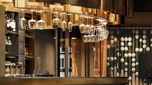 A bar area with stools, a hanging light fixture, and a wall with spherical decorations. - The Brick, a Tribute Portfolio Hotel - Adults Only (Gdansk)