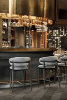 A bar area with stools, a hanging light fixture, and a wall with spherical decorations.