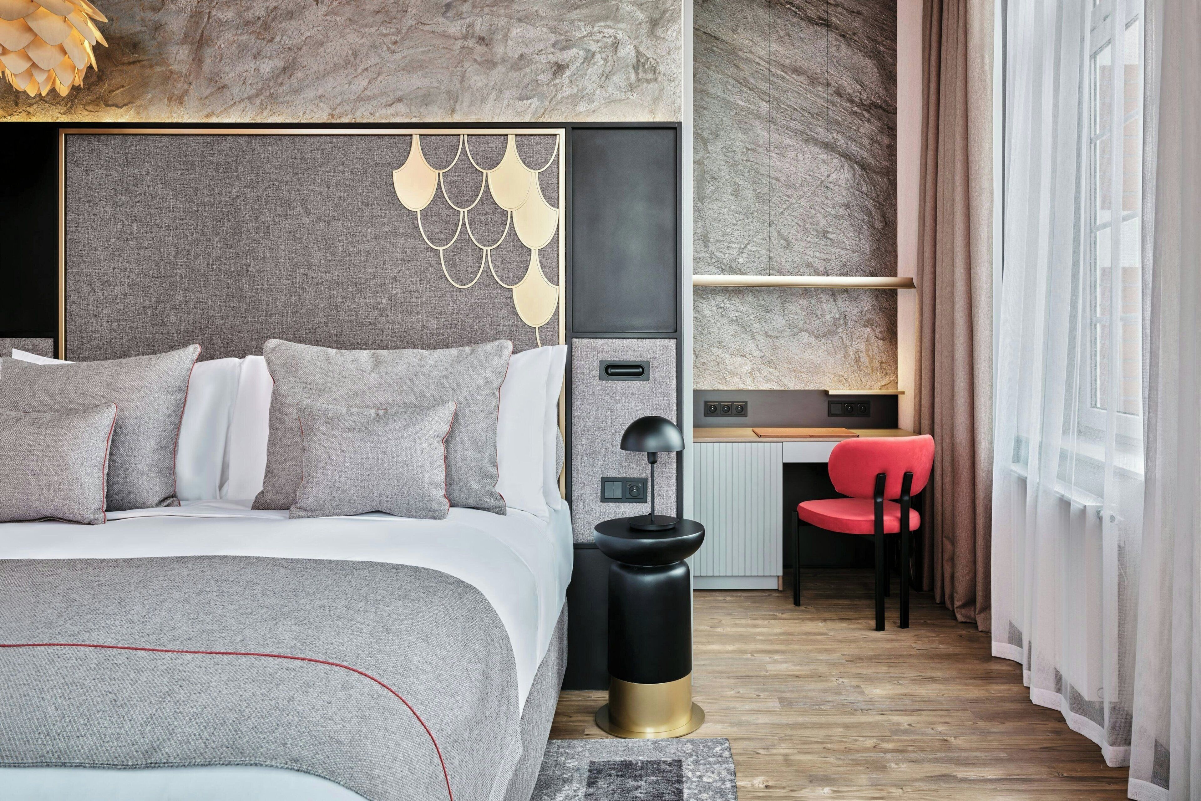 Ein modernes Hotelzimmer mit einem großen Bett, einem Schreibtisch und einem Stuhl.